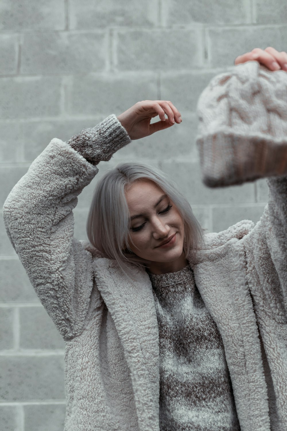 woman in gray sweater holding her hair