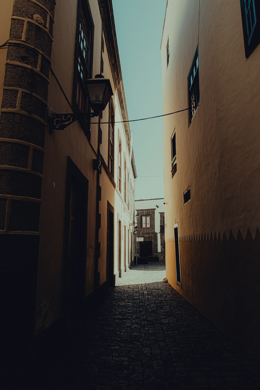 brown brick pathway between brown concrete buildings during daytime