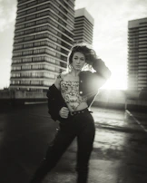 Sunlit photo of a person standing tall on a rooftop, wearing a jacket that embodies integrity and visible action.