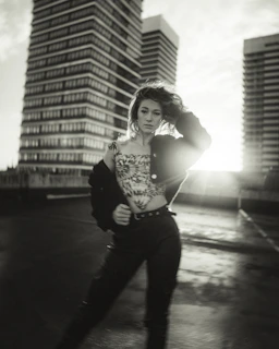 Sunlit photo of a person standing tall on a rooftop, wearing a jacket that embodies integrity and visible action.