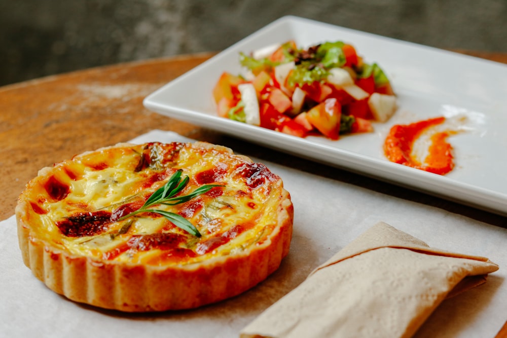 Pizza con hoja verde sobre bandeja de cerámica blanca