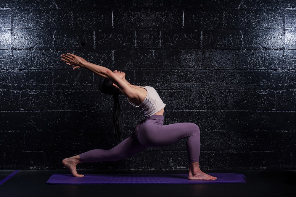 Frau in grauem Tanktop und Leggings beim Yoga