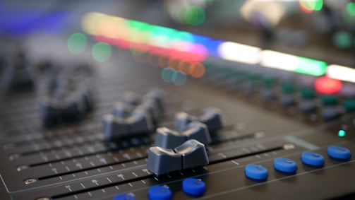 Sound mixing console with colorful lights and sliders.