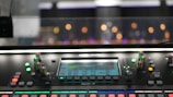Close-up of mixing console with colorful lights and knobs during music production.
