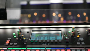 Close-up of broadcast-quality audio mixer with glowing controls in a dark studio.