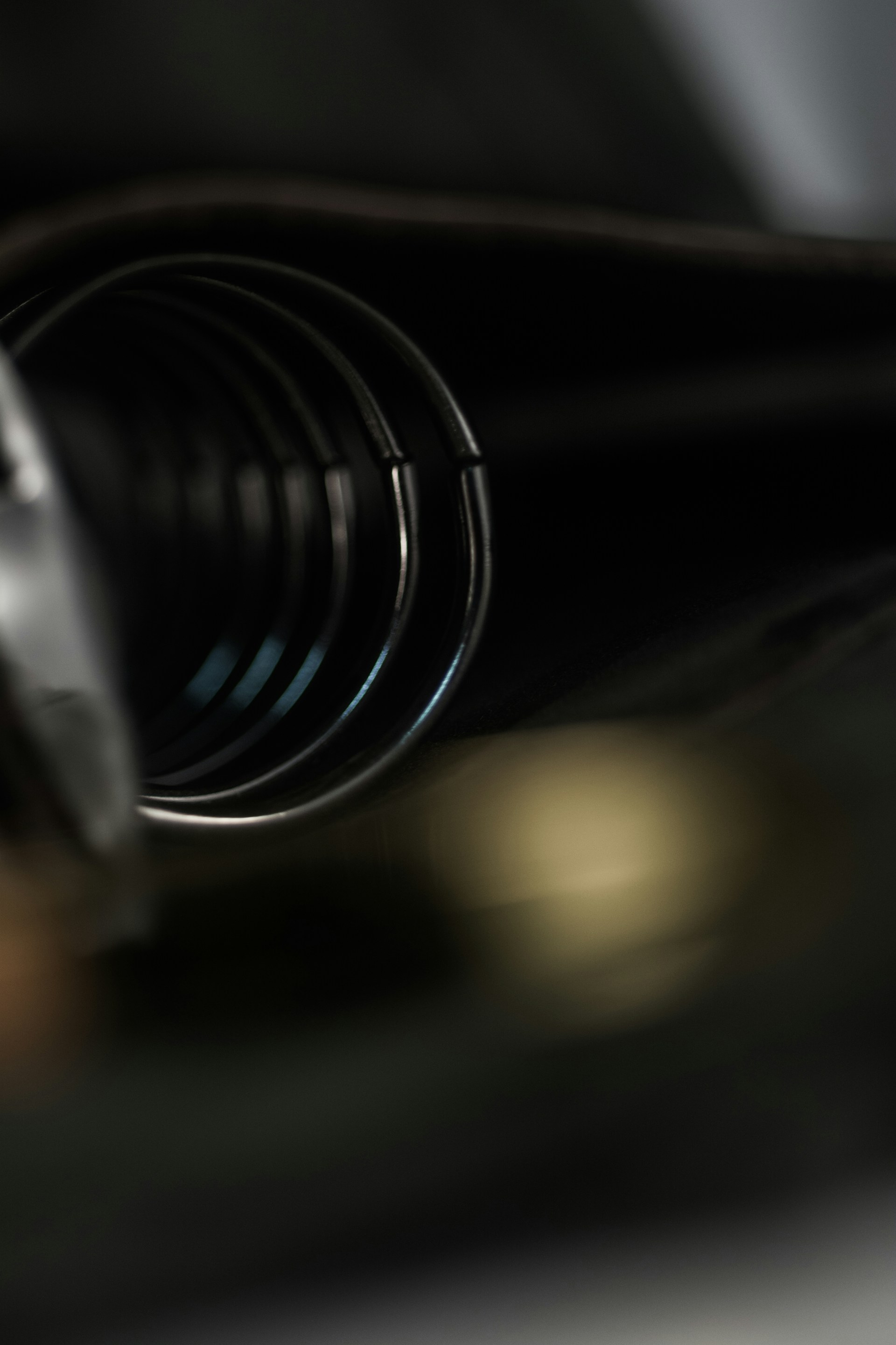 Close-up of a shiny torsion spring perfectly coiled, resting on a vintage Spinjas game launcher with a softly worn wooden table background.