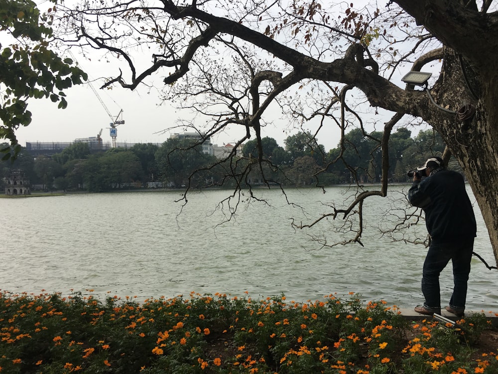 man in black jacket standing near body of water during daytime