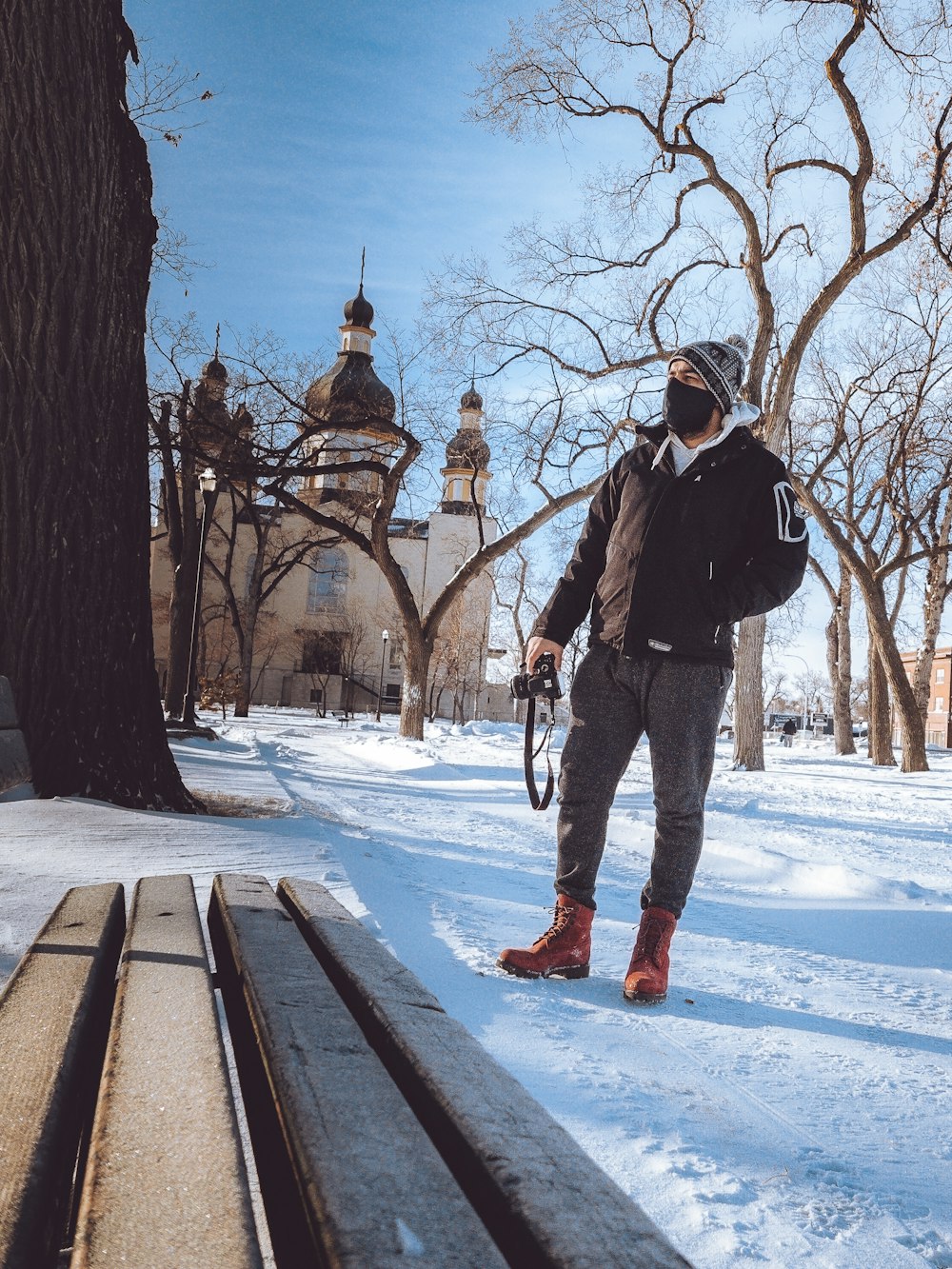 man in black jacket and red pants standing on snow covered ground during daytime