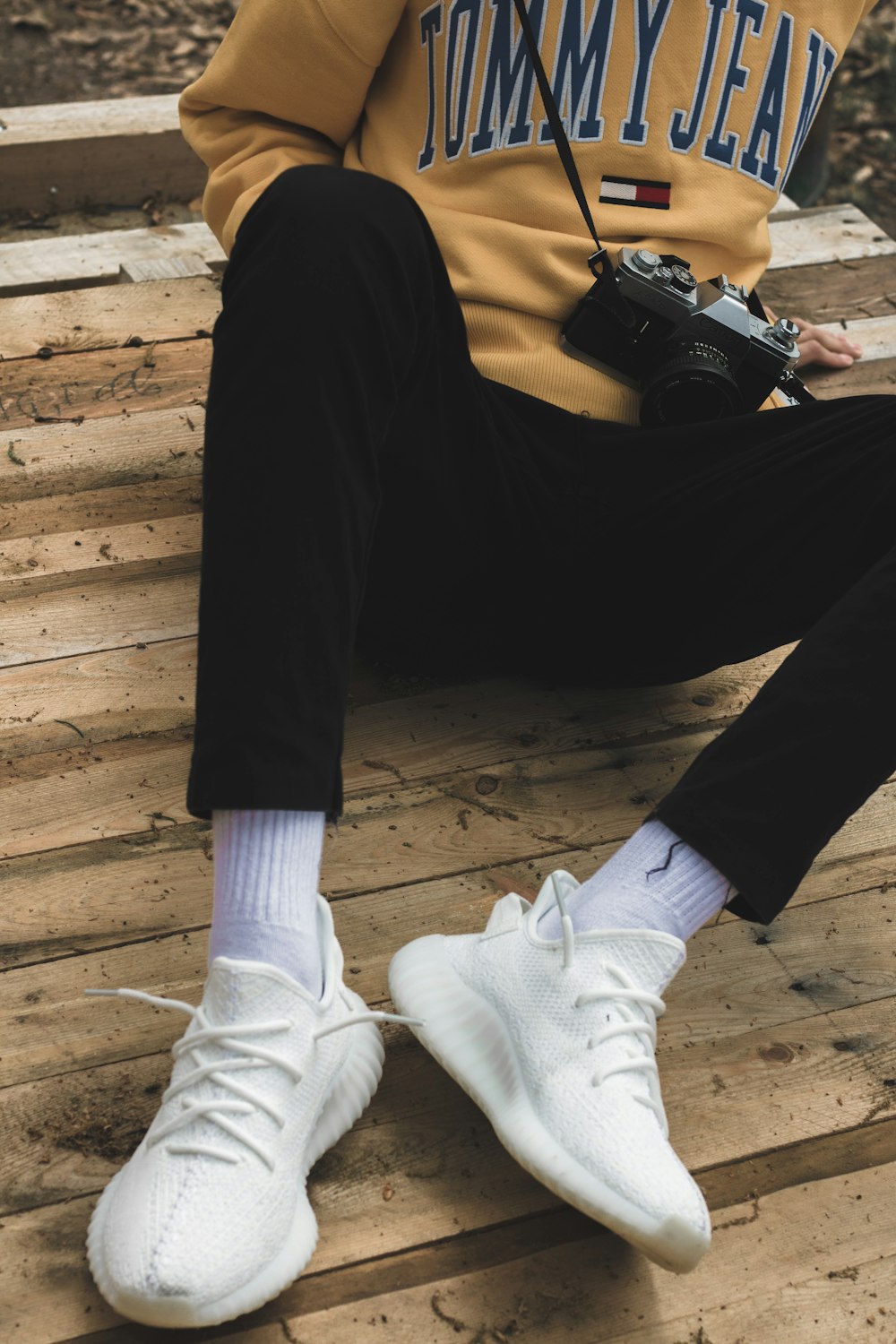 Persona con pantalones negros y calcetines blancos sentada en el piso de madera marrón