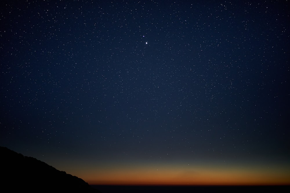 silhouette of mountain under blue sky during night time