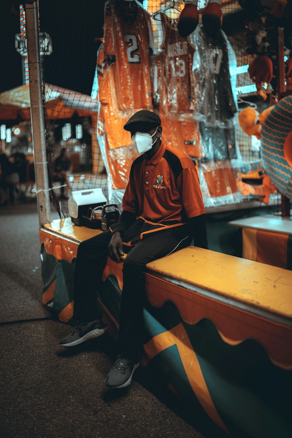 man in red and black long sleeve shirt sitting on brown wooden bench