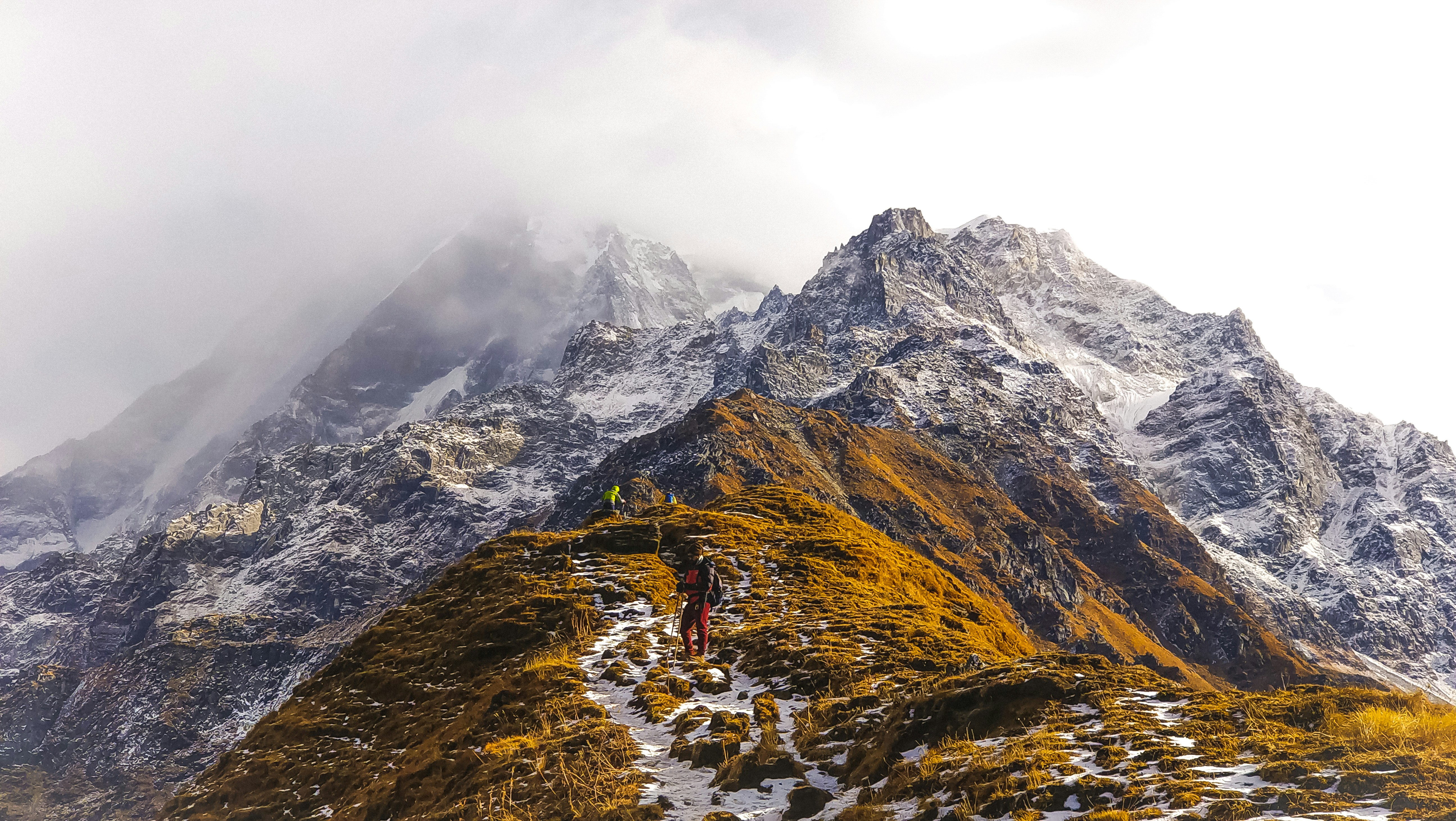 person in brown jacket standing on rocky mountain during daytime