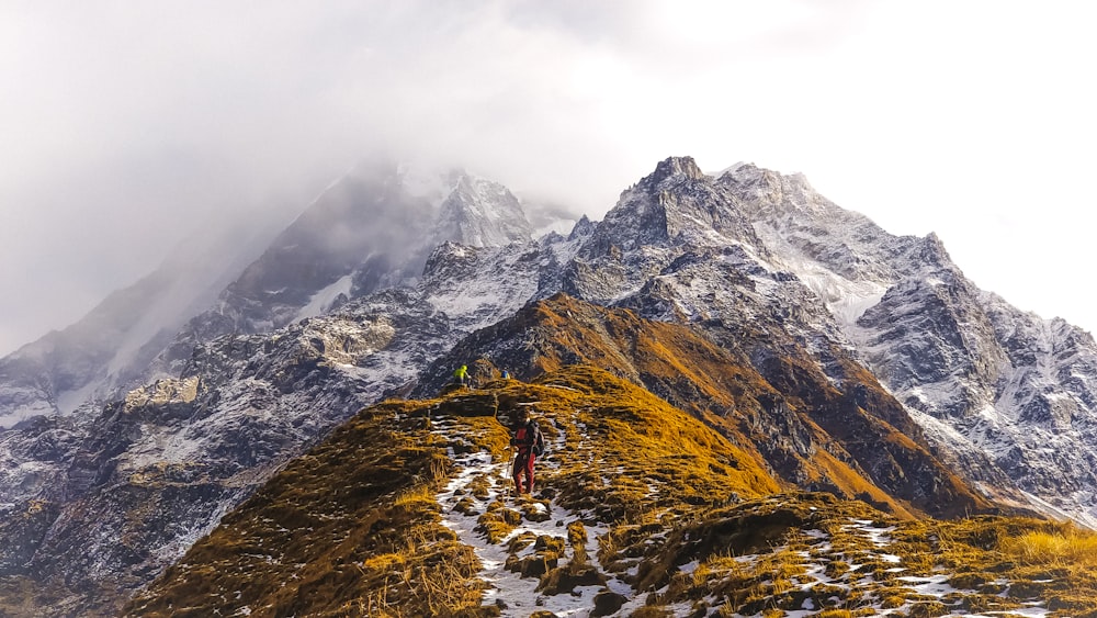 Persona en chaqueta marrón de pie en la montaña rocosa durante el día