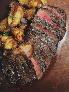 Close-up of a sizzling steak served with roasted potatoes and herbs.