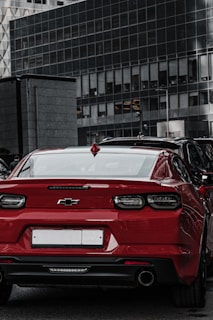 Side profile of a red Chevrolet Onix parked near a park.