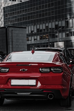 Side profile of a red Chevrolet Onix parked near a park.