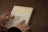 A close-up of hands unwrapping the páginaclave book from rustic packaging.