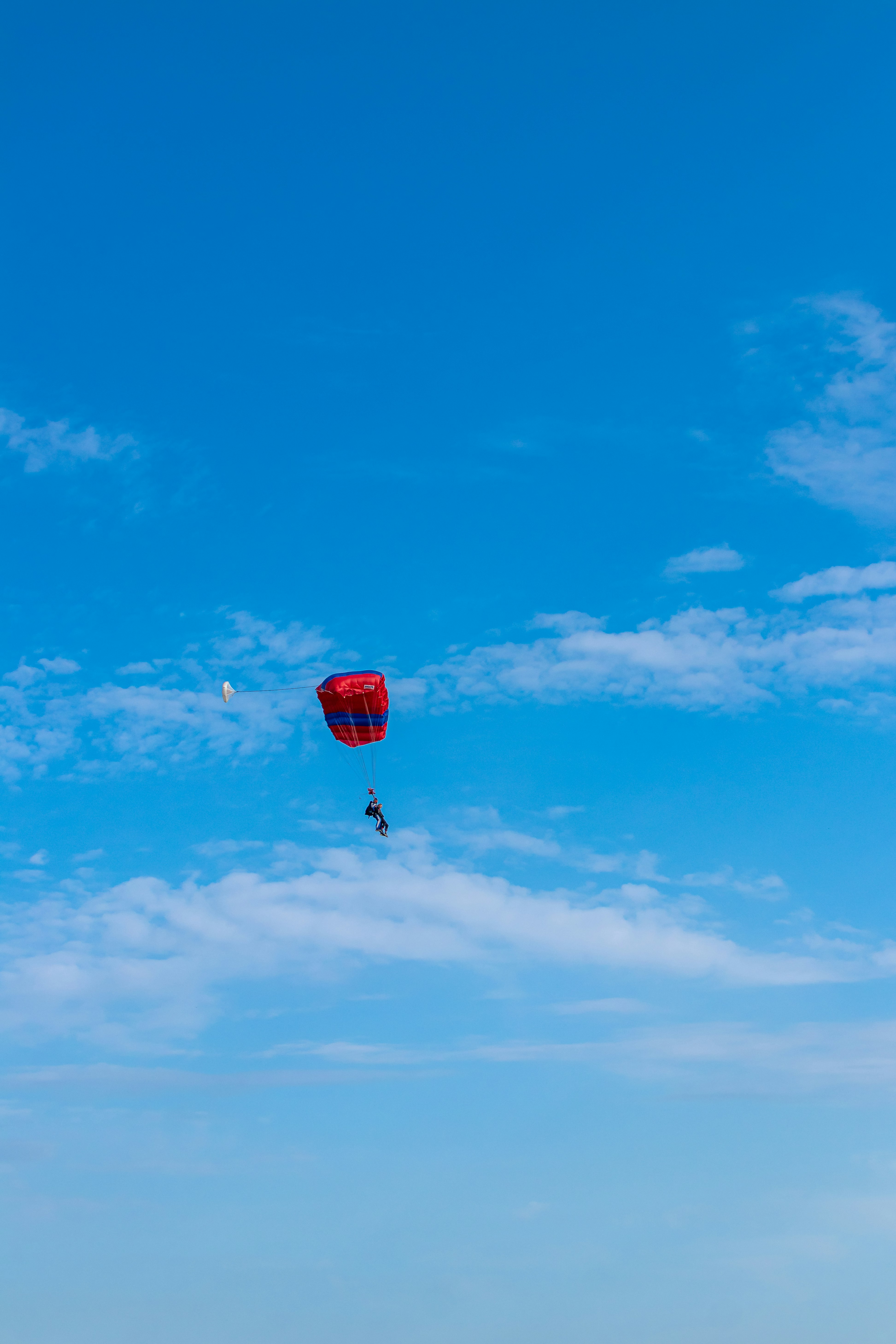 red and white parachute under blue sky during daytime