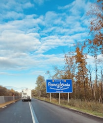 blue and white road sign near trees during daytime