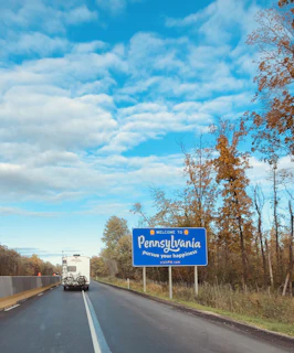 blue and white road sign near trees during daytime