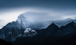 A dramatic mountain peak under swirling clouds just before a storm.