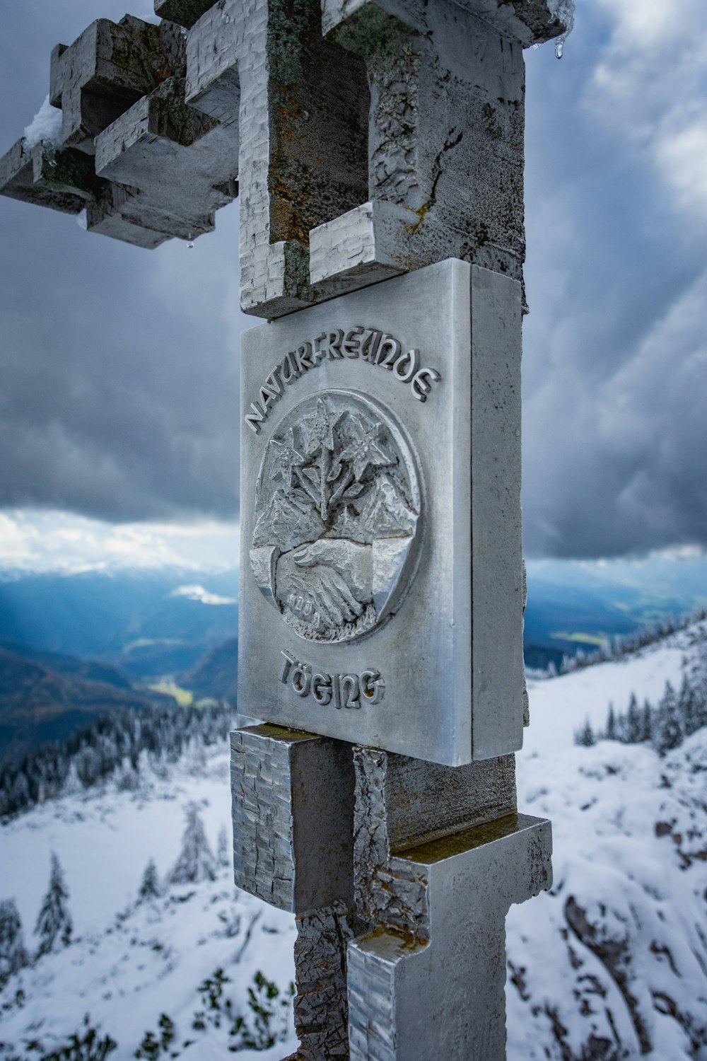 grey concrete cross with mountain in distance