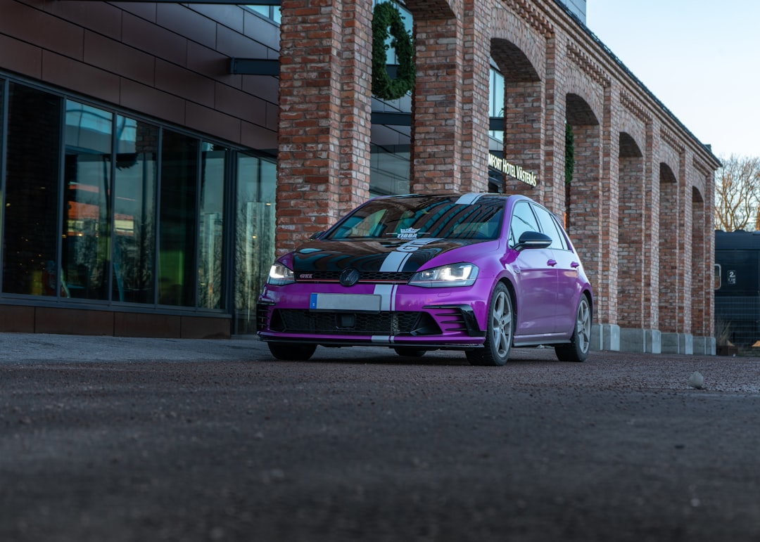 purple sedan parked beside brown concrete building during daytime