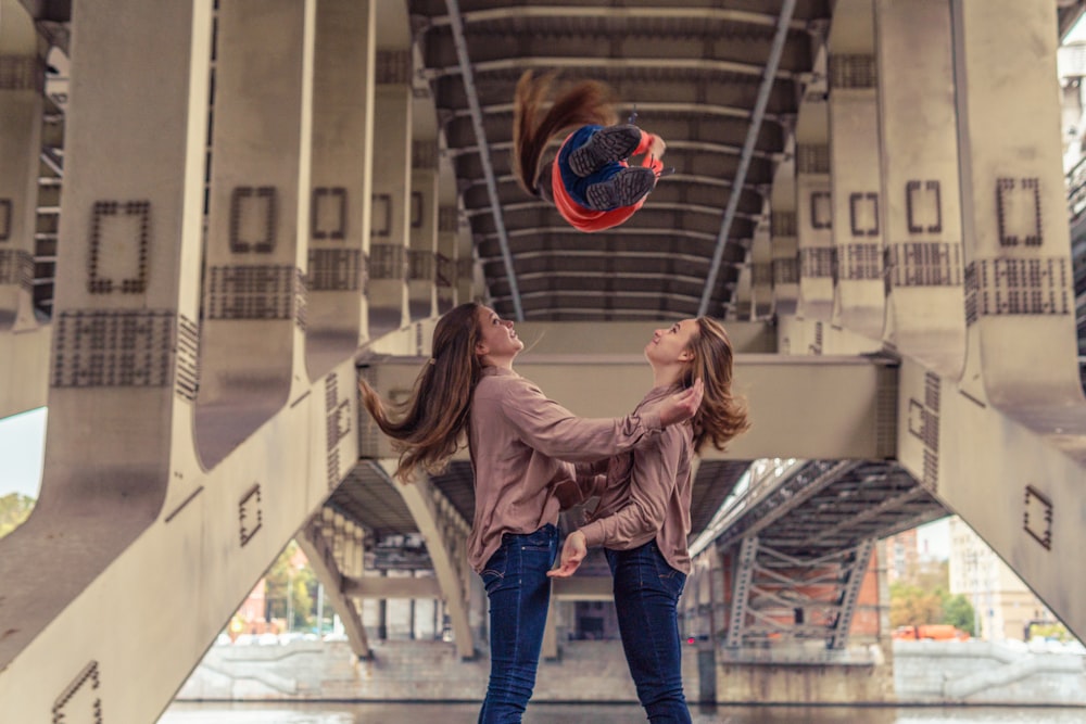 2 women in pink long sleeve shirt and blue denim jeans standing on gray metal frame