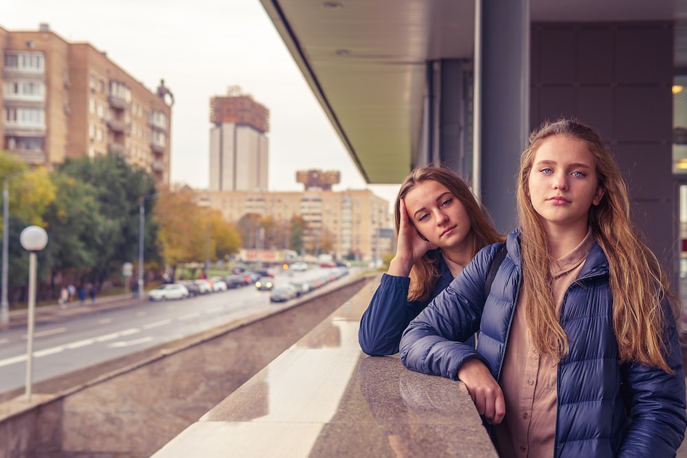 woman in brown leather jacket sitting on concrete bench during daytime