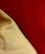 A close-up of textured fabric with a smooth, shiny golden cloth lying over a rich, vibrant red background. The fabric appears to be draped, showing natural folds and shadows, which highlight the different textures and surface qualities of the materials.