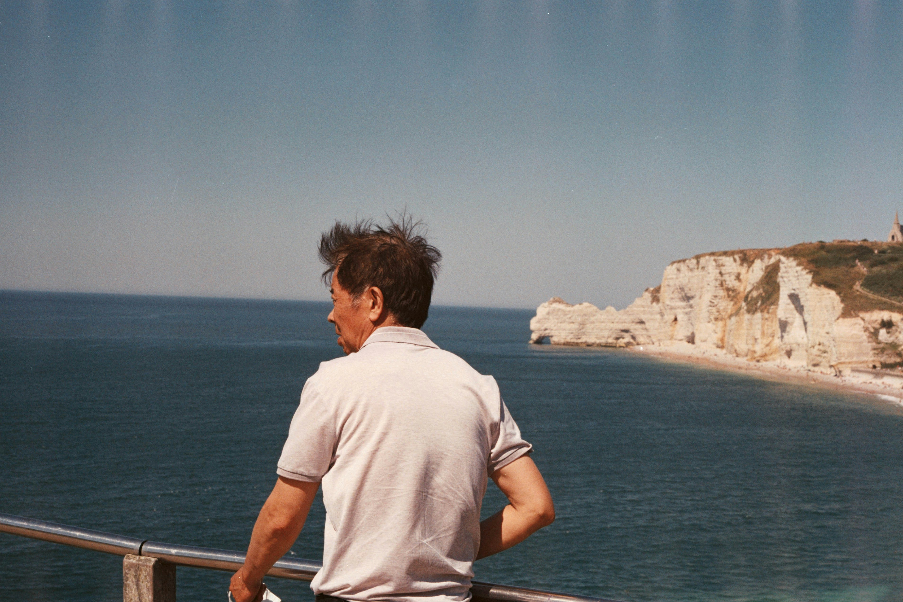 woman in white t-shirt standing on brown wooden dock during daytime