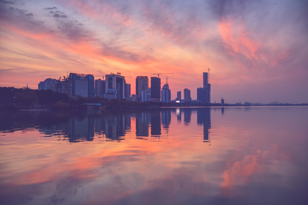 city skyline across body of water during sunset