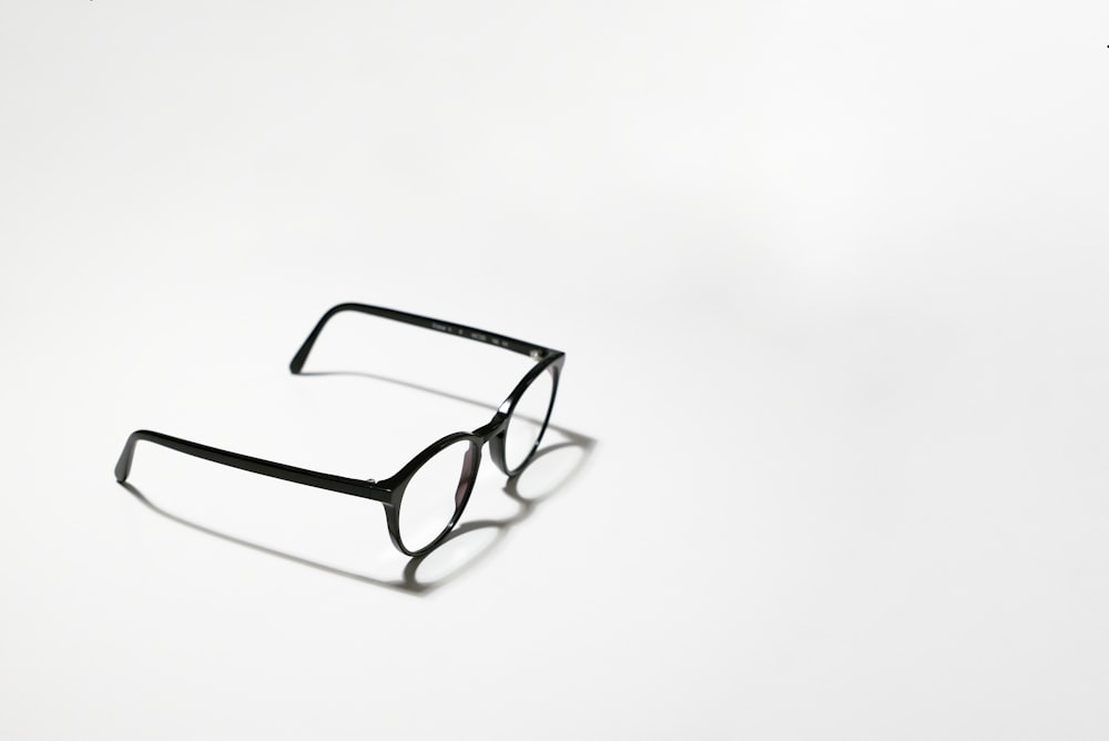 gafas de montura negra sobre superficie blanca