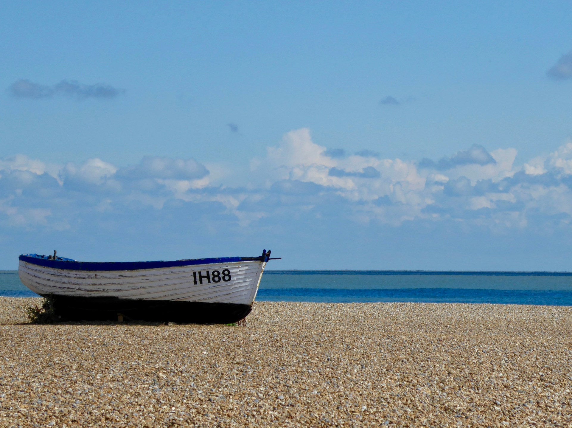 white and blue boat on brown sand under blue sky during daytime