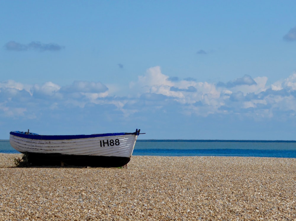 white and blue boat on brown sand under blue sky during daytime