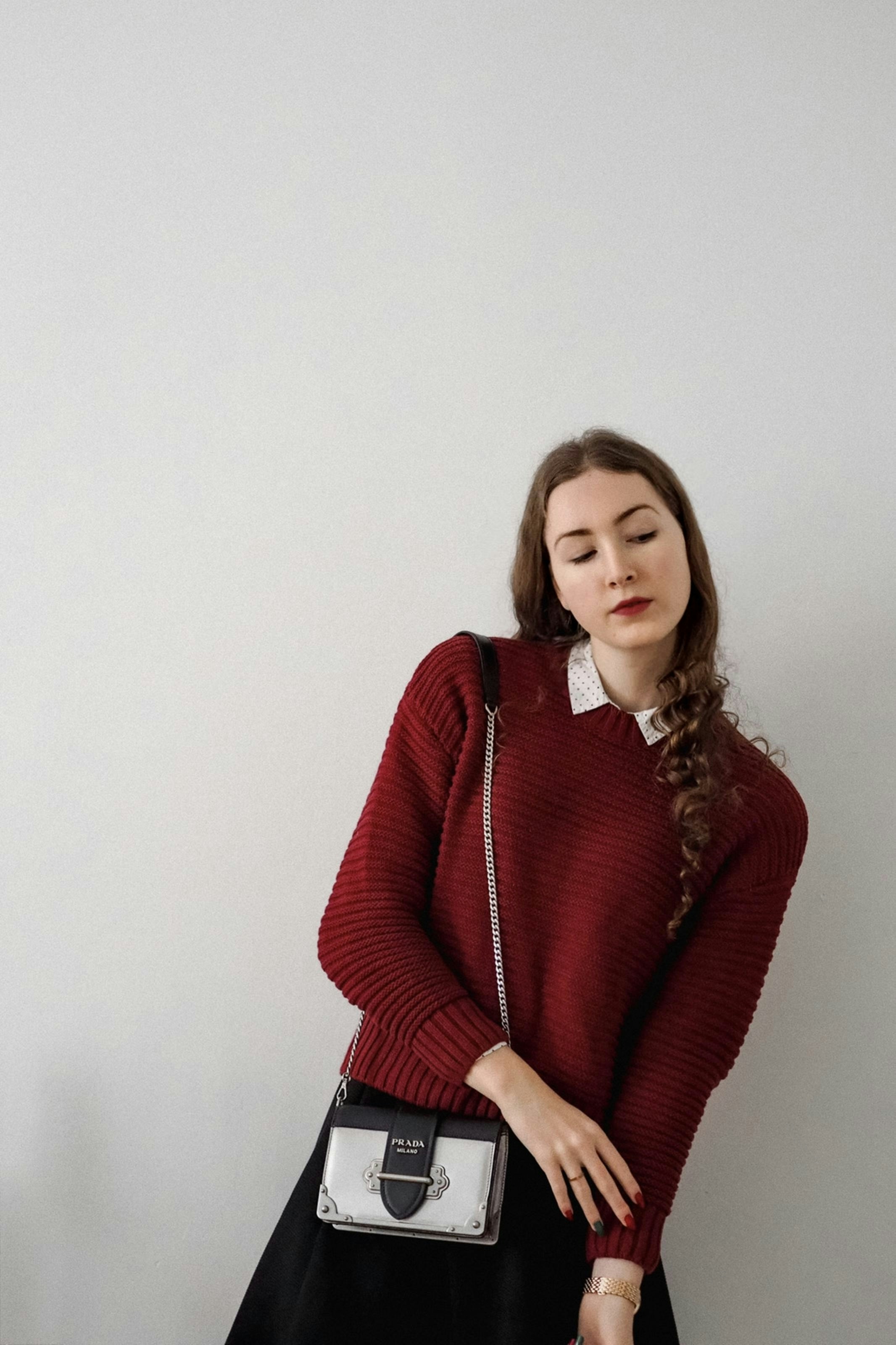 Tas shoulder strap warna hitam elegan di bahu wanita muda dengan pakaian formal kasual