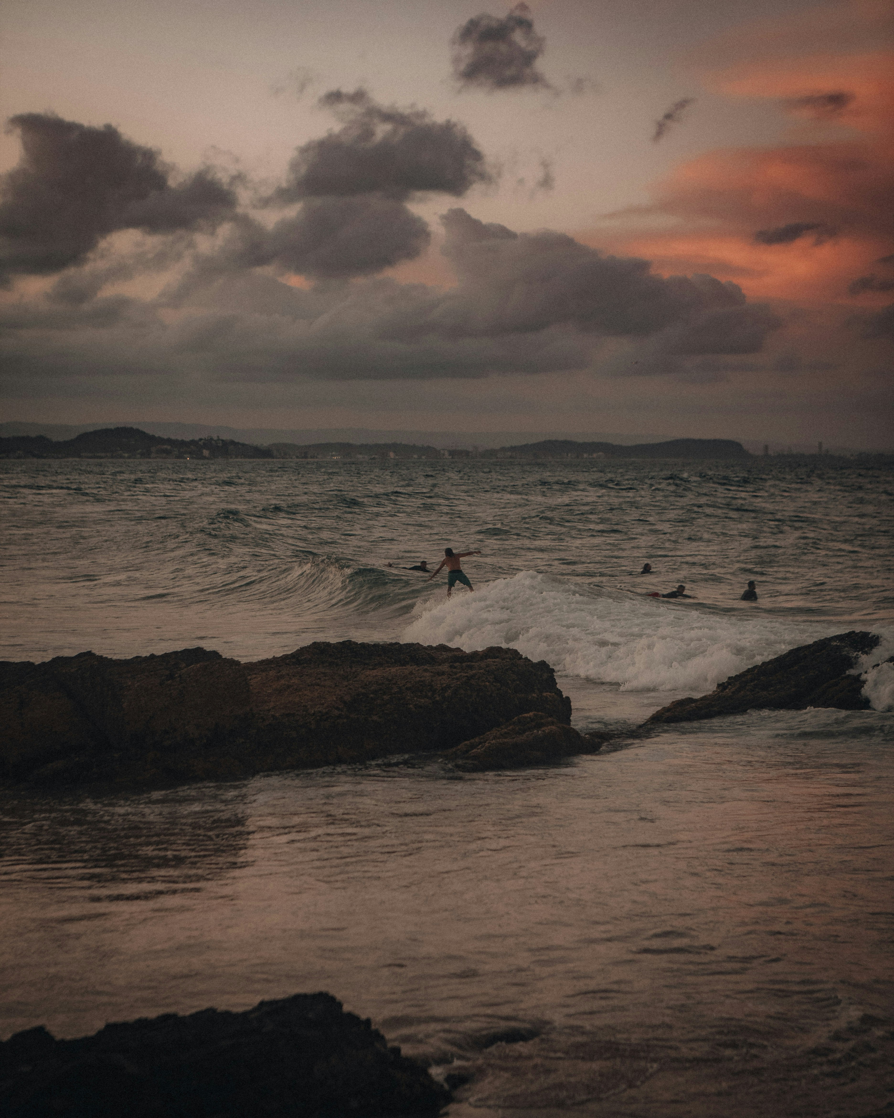 person standing on rock near sea during sunset
