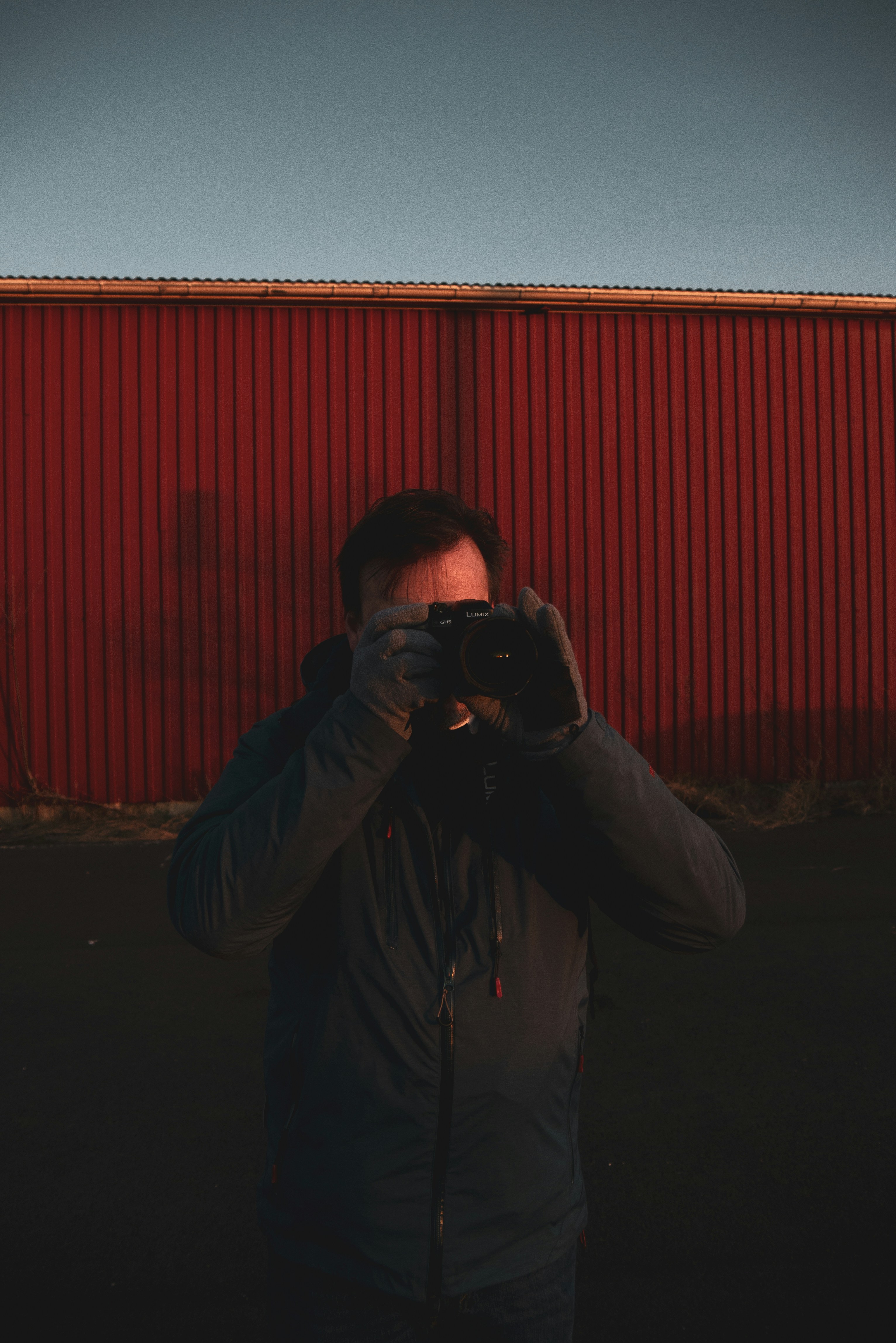 homem na jaqueta cinza segurando a câmera dslr preta