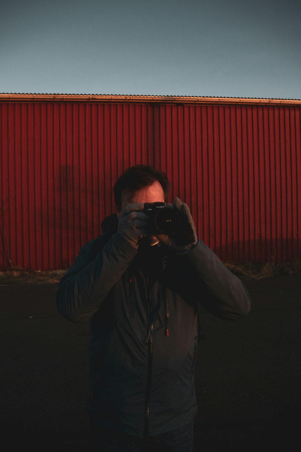 man in gray jacket holding black dslr camera