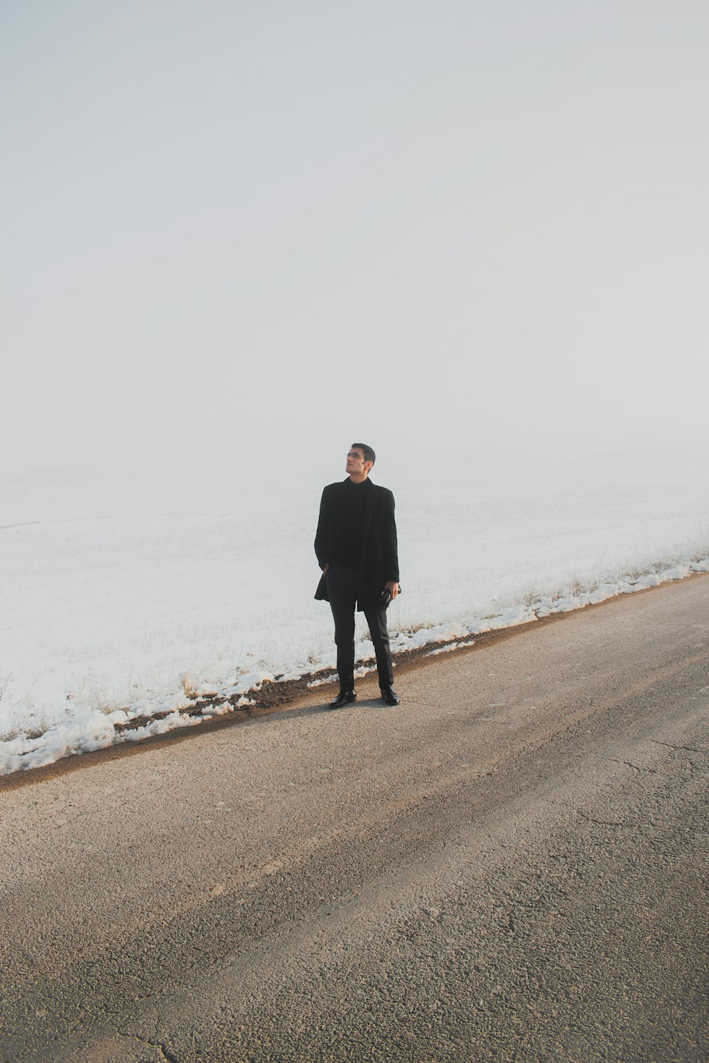 man in black coat walking on gray sand during daytime