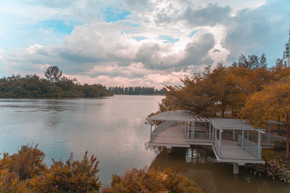 white and black house near body of water under cloudy sky during daytime