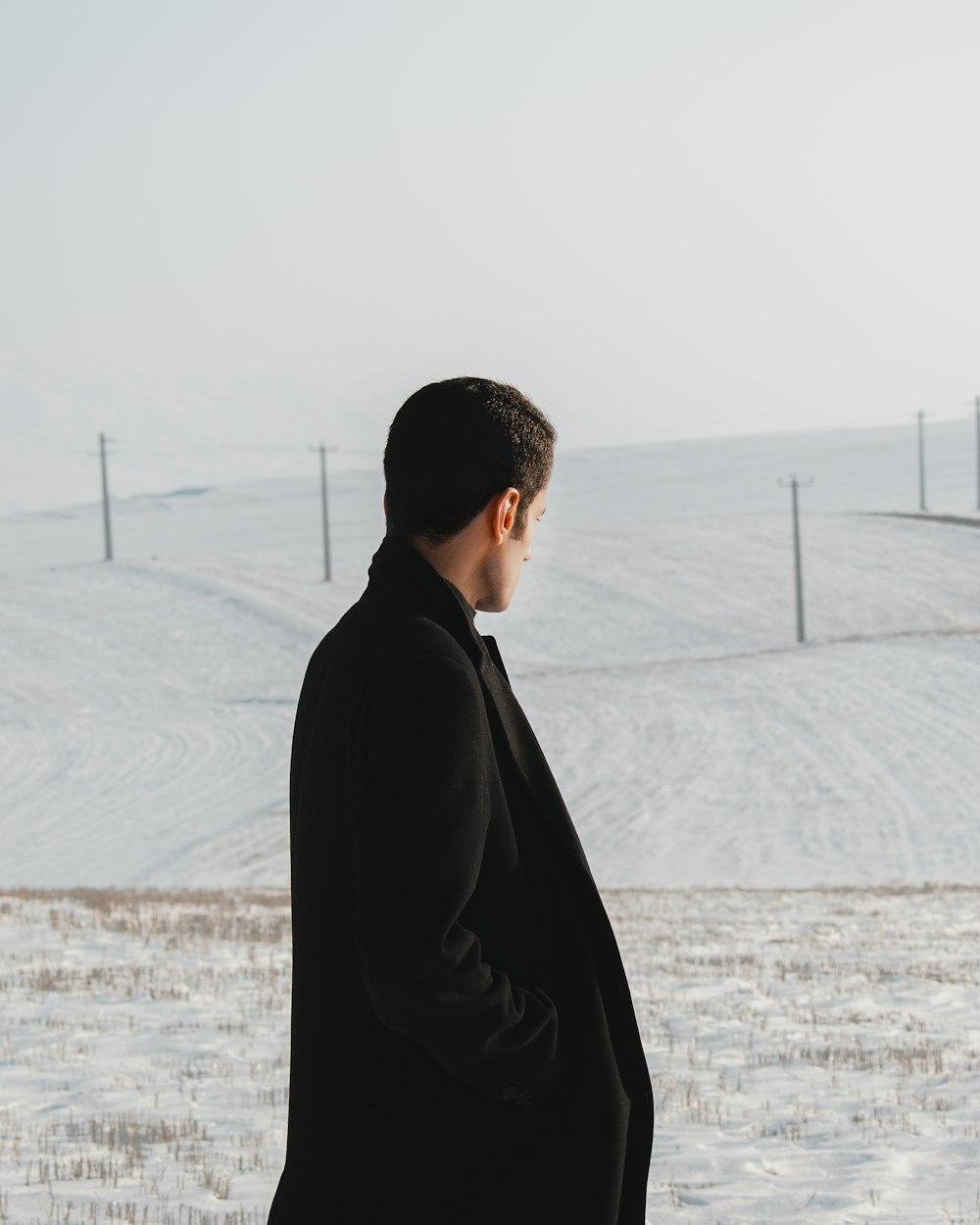 man in black coat standing on snow covered ground during daytime