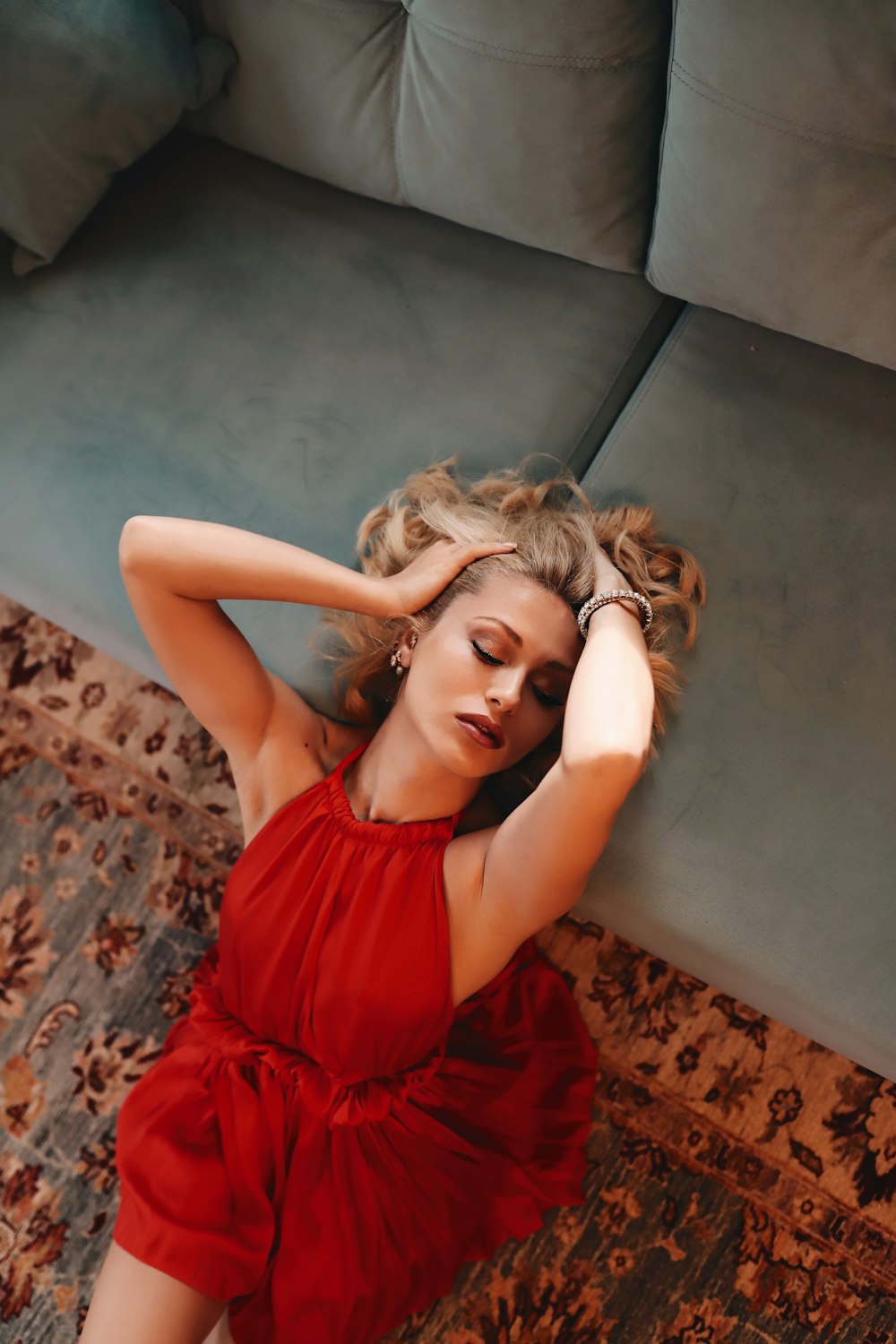 woman in red sleeveless dress lying on brown floral textile