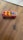 A colorful toy car with flame decals is placed on a wooden surface. The car is predominantly red with yellow seating and black wheels. It features a sleek design with hot rod styling and a label on the front.
