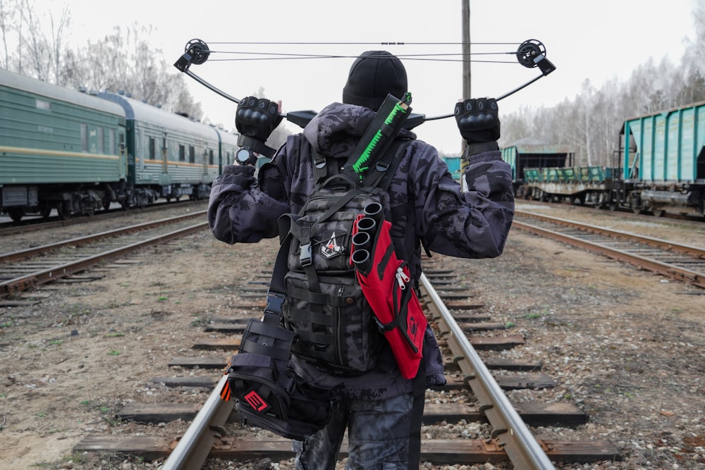 검은 재킷과 녹색 헬멧을 쓴 남자가 낮 동안 기차 레일에 서 있다