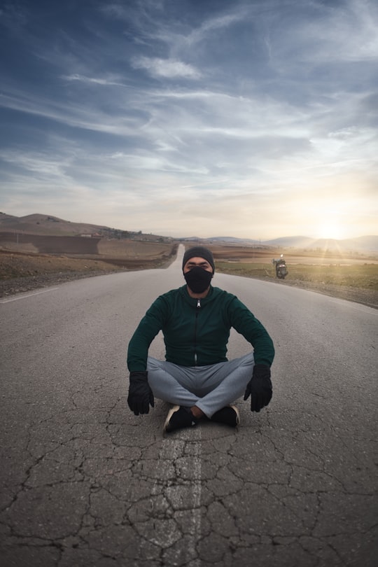 man in gray hoodie sitting on road during daytime in Djelida Algeria