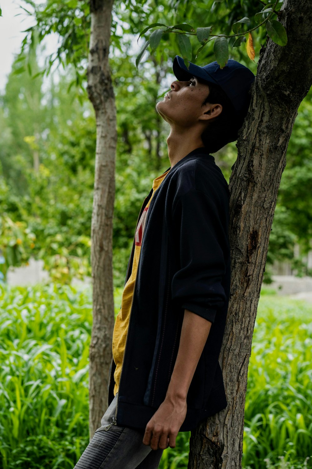 man in black shirt standing beside tree during daytime