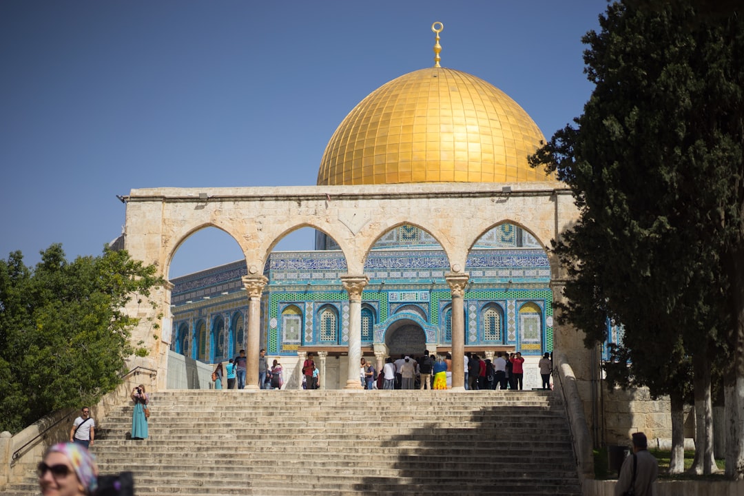 people walking near brown and white dome building under blue sky during daytime