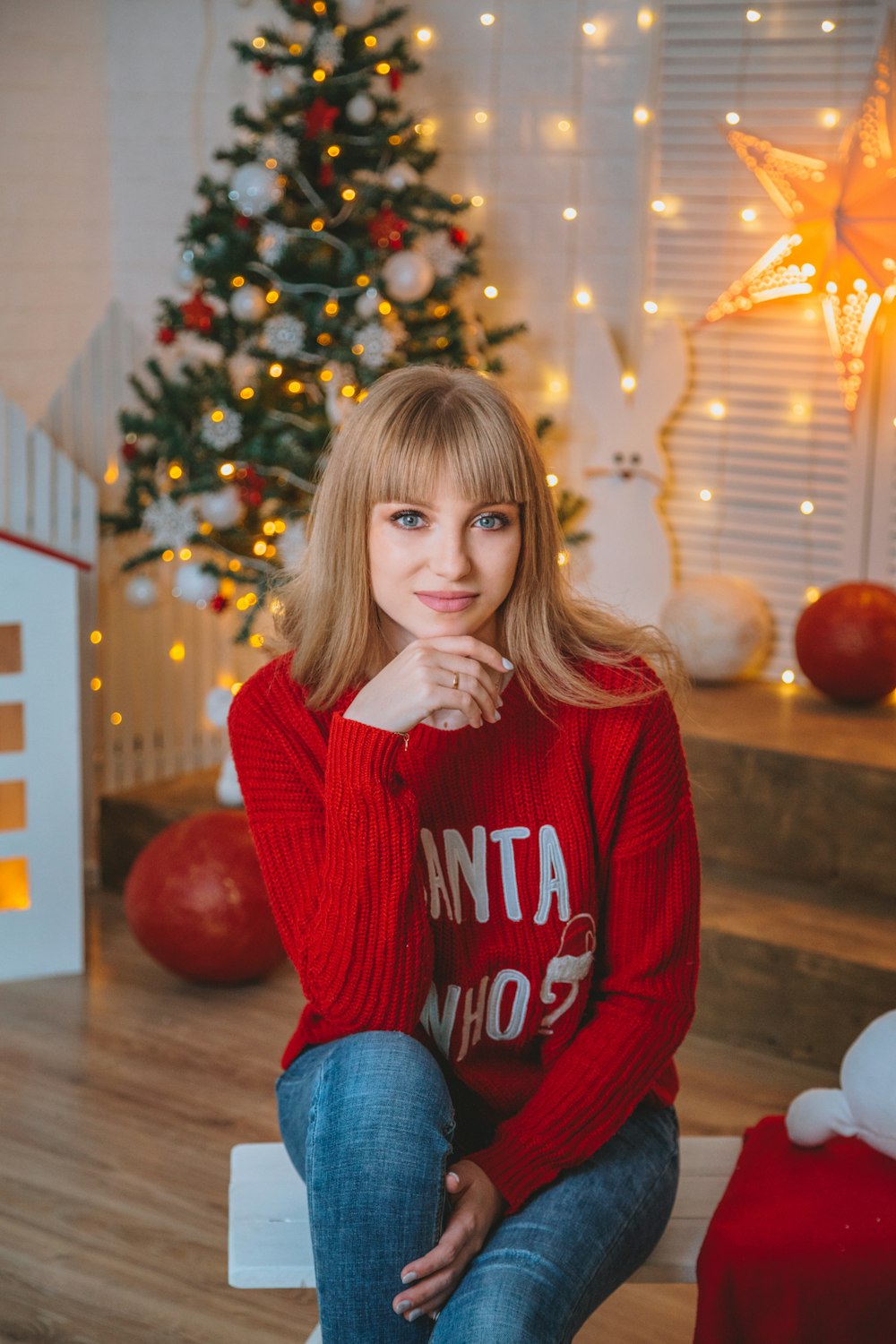 girl in red and white sweater and blue denim jeans sitting on floor