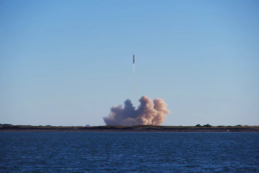 A rocket launching into a clear blue sky over a launchpad